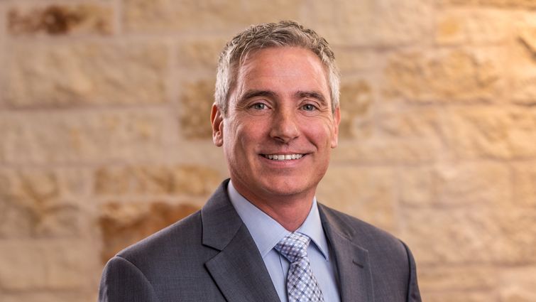 portrait photo of Caucasion man with grey hair in grey suit with light blue shirt and tie