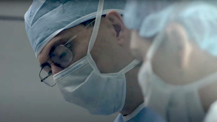 Daniel DiLorenzo, MD, PhD, MBA, is the leading expert of the technology surrounding closed-loop neuromodulation A close up if two doctors with blue face masks and blue net caps in an operating room