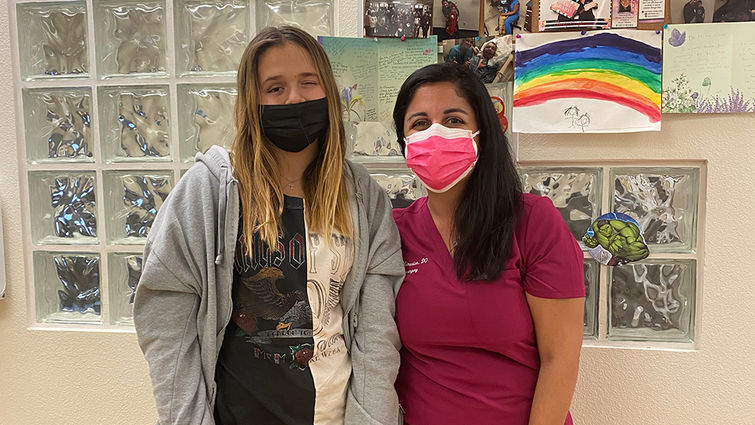 tall female patient poses for photo, hugging smiling female doctor in scrubs