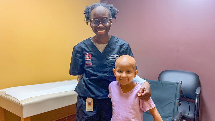 female doctor stands with female patient next to wheelchair, both smiling