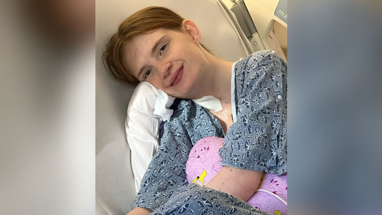 Emily Conant looks at camera while lying in hospital bed