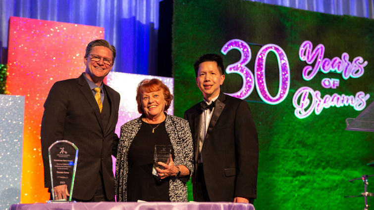 Caucasian man, Caucasian woman and Asian man in formal wear, presenting an award.  man, 