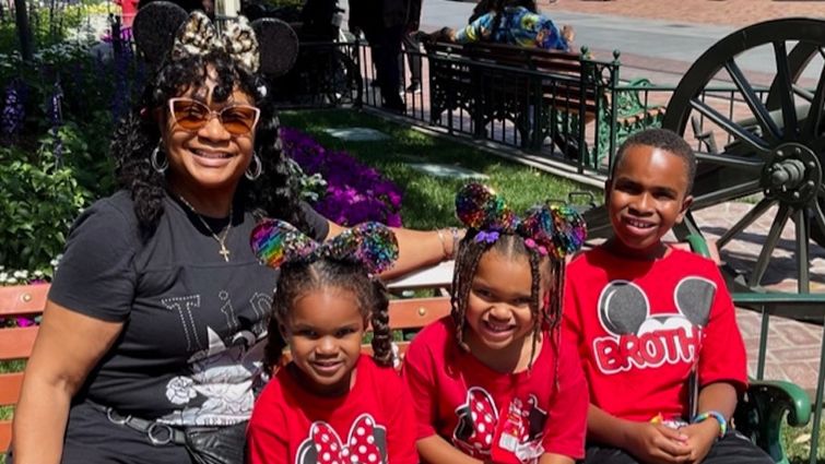 Gaylyn sitting on bench at Disneyland with her three grandchildren. Two girls, one boy