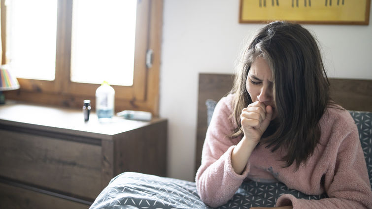 White woman coughing in bed with asthma