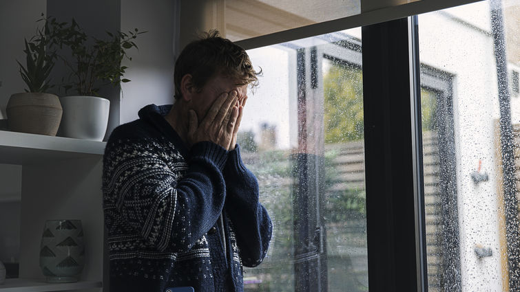 Man by window - head in hands - stock photo