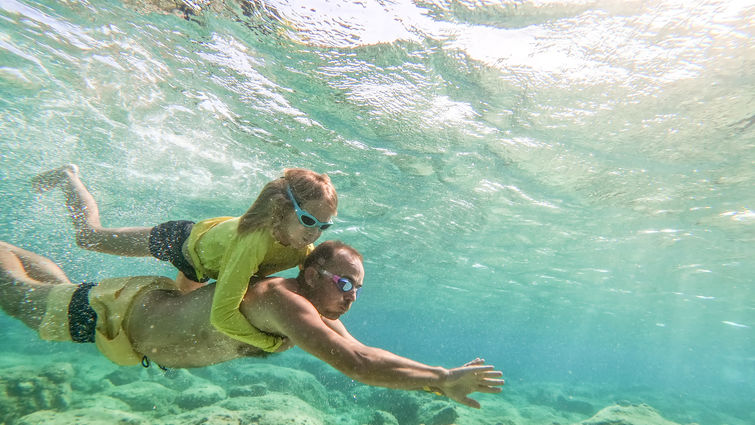 dad and daughter swimming under water