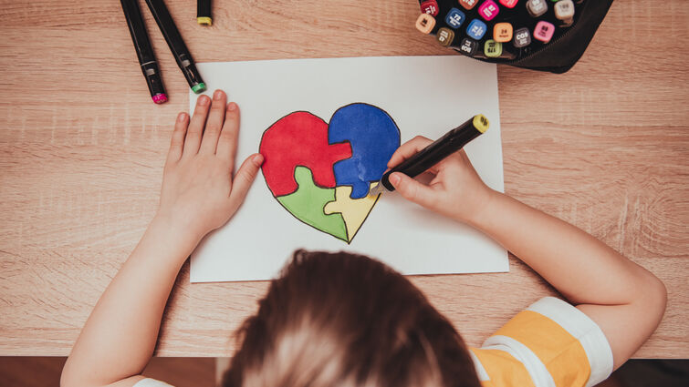 World Autism Awareness day. Children's hand draws heart from multi-colored puzzles. Mental health care concept