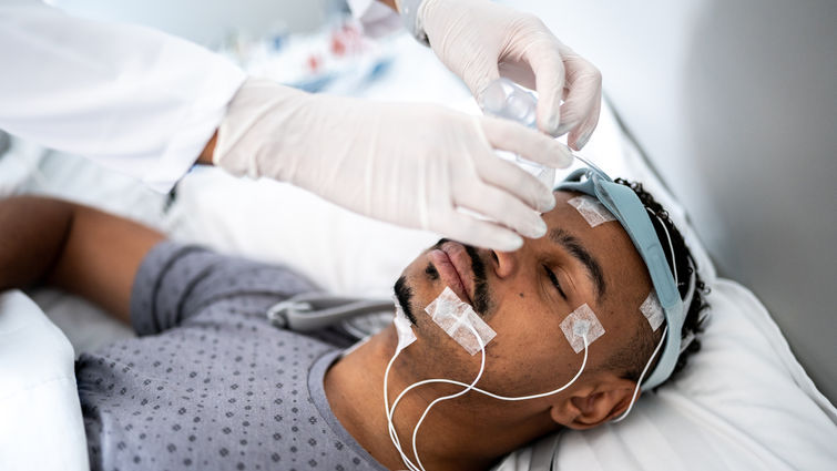 Doctor preparing patient in bed for polysomnography (sleep study) - stock photo