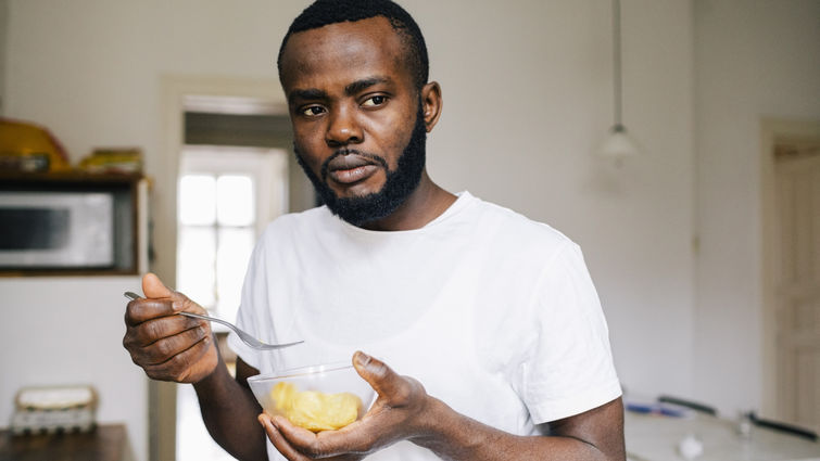 man standing holding bowl of food looking stressed