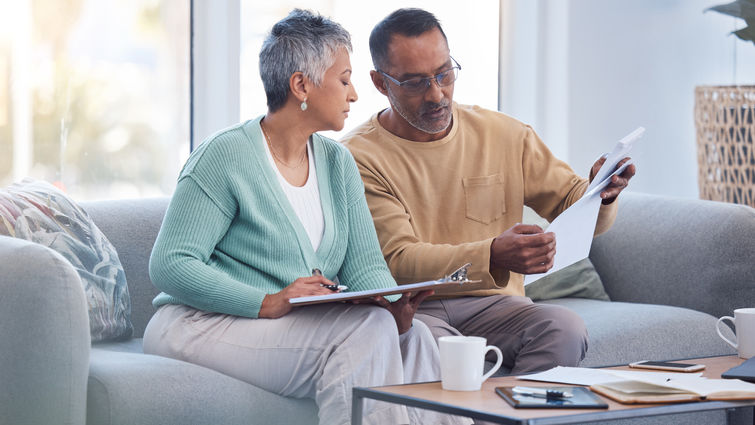 Couple sitting on couch reviewing paperwork