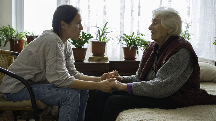 Young woman holding old woman's hands during conversation