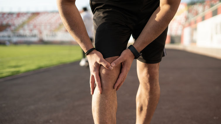 Unrecognizable sports man injures his knee while jogging 