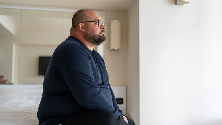 Middle aged white man sitting on bed stressed out