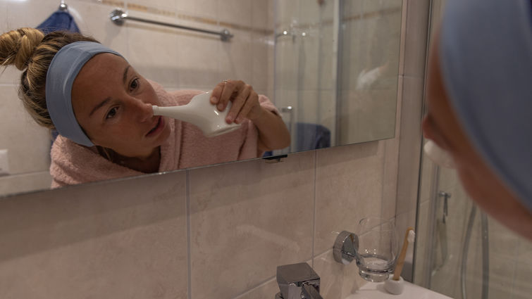 Woman using a natural nasal saline irrigation to clean her nose. Neti pot - stock photo