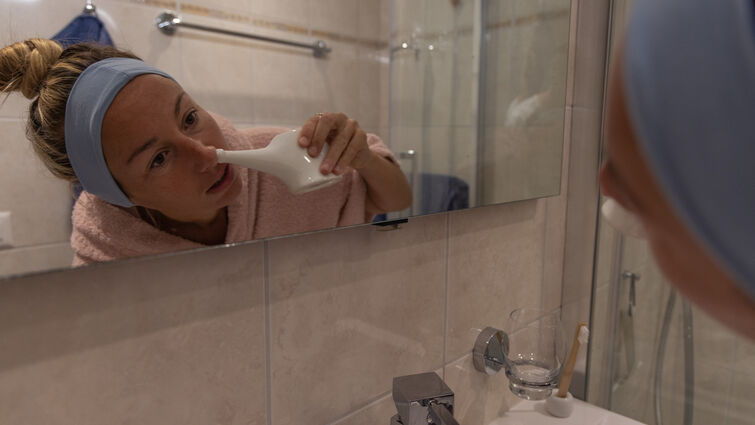 Woman using a natural nasal saline irrigation to clean her nose. Neti pot - stock photo