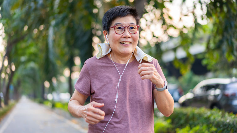 A senior woman wearing earphones while walking for exercise.