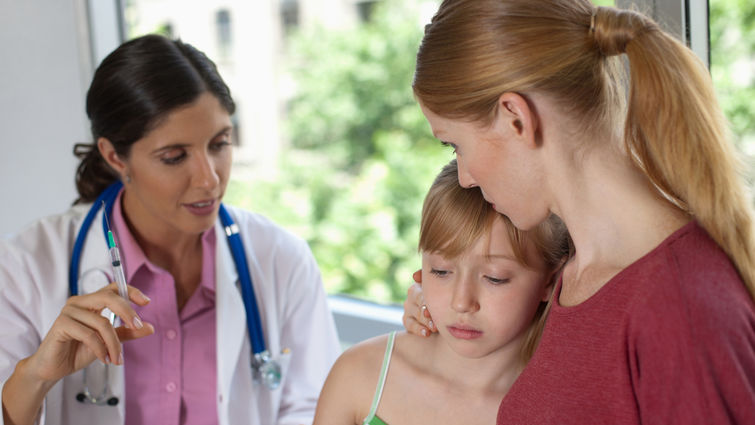 Doctor about to give young scared patient an injection - stock photo