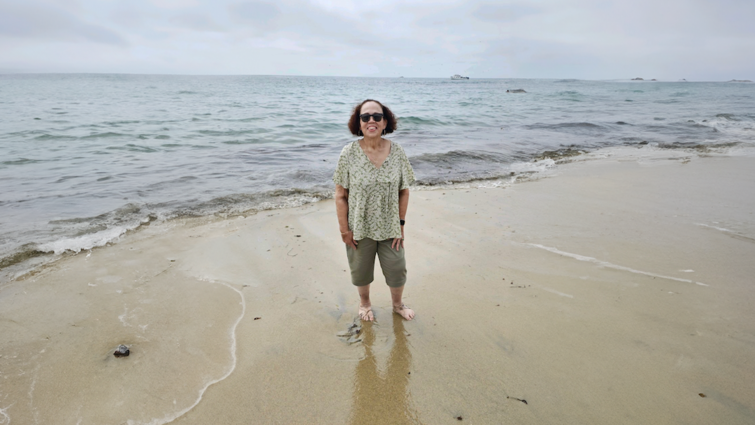 After eight years of not being able to straighten her knees, Gina Reynolds regained her ability to walk A female stands in the sand on the beach on an overcast day with the ocean water behind her