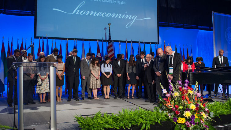 Students planning to serve internationally are the focus of a dedicatory prayer during the 'One Homecoming' worship service.