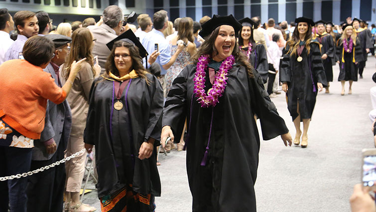 Two graduates from the School of Allied Health Professions walk down the aisle during their commencement ceremony