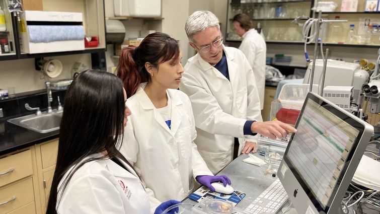 Dr. Arlin Blood conducts research with two students.