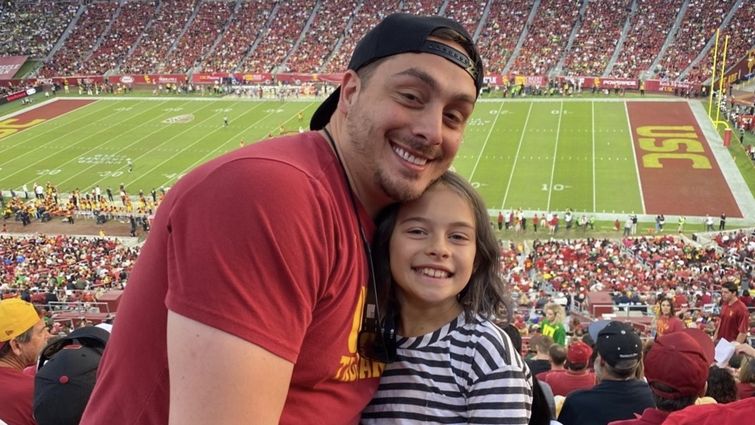 Desena watches a football game with his daughter at his alum USC