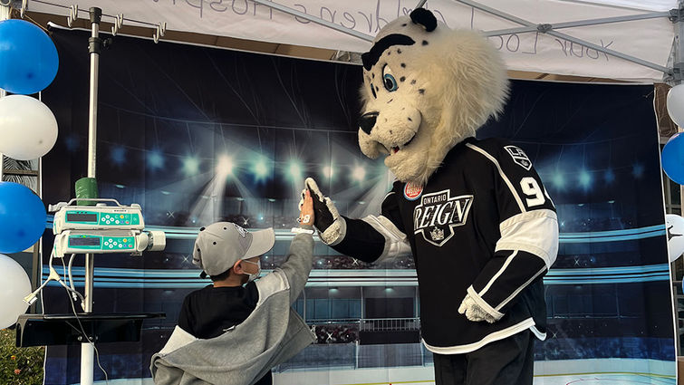 A patient high-fives mascot Kingston during the Ontario Reign hockey team's December 14 visit to Loma Linda University Pediatric Specialty Team clinics.