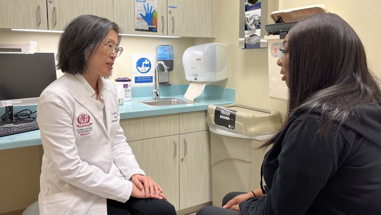 Sharon Lum, MD, MBA, chair of the LLUH Department of Surgery speaks with a breast cancer patient in a clinic room.