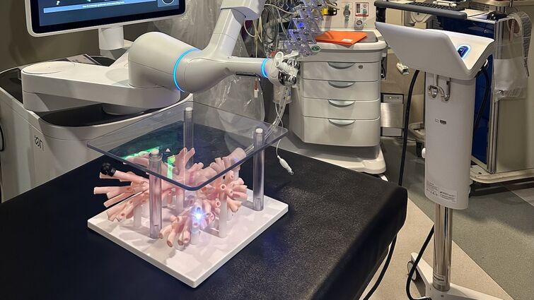 The large, white ION Robotic arm is positioned over a replica of the lungs on a black table