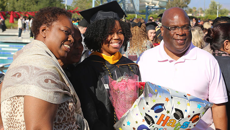 A graduate commemorates the moment, posing for a photo with loved ones.