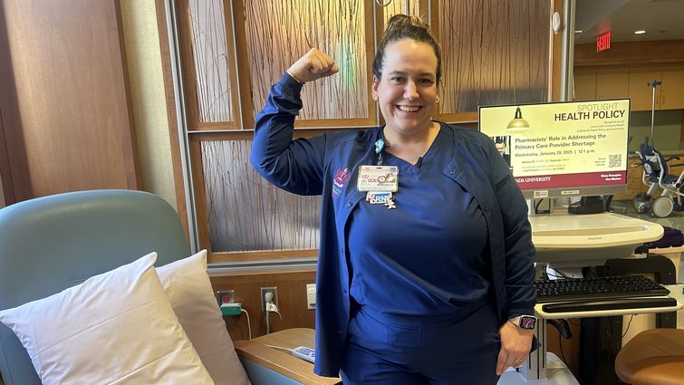 White woman in scrubs flexing her arm to signify strength.