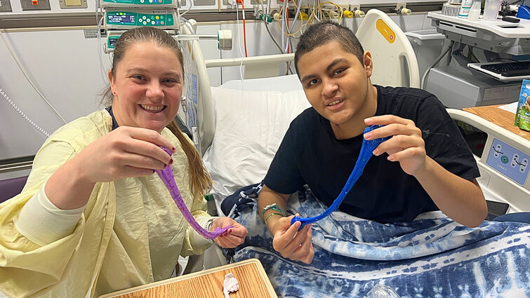 Child life specialist and patient play with slime they made at the patient bedside