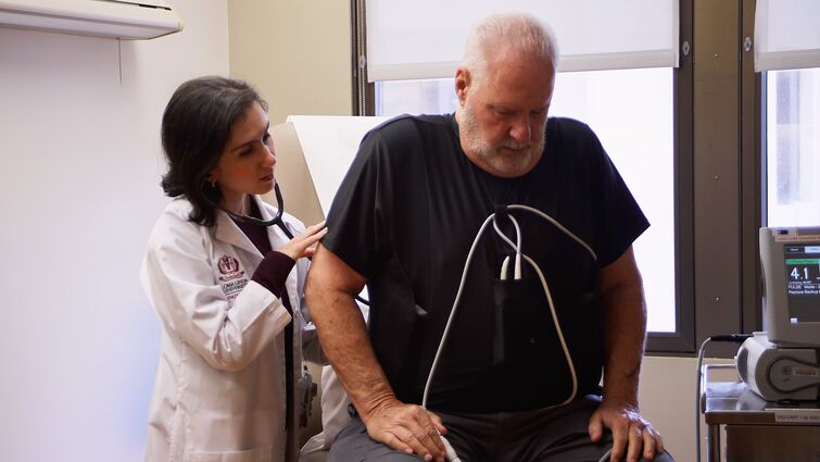 A doctor uses her stethoscope to listen to a patient's heart 