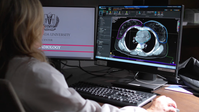 A woman looks at a computer screen with a medical scan