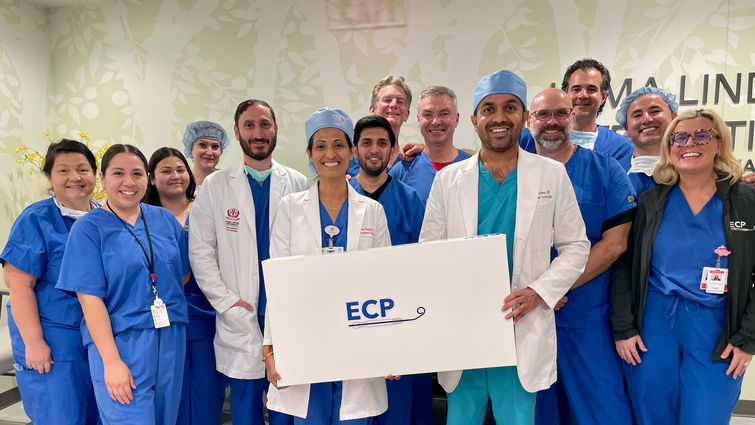 The LLU cardiologists (in white coats from left) Drs. Ahmed Seliem, Pooja Swamy, and Aditya Bharadwaj worked with their research and cath lab teams, as well as Abiomed administrators, engineers, and trainers to successfully implant the Impella ECP on April 28. LLU cardiology research and cardiac cath lab team with Abiomed team on day of first Impella ECP implant.
