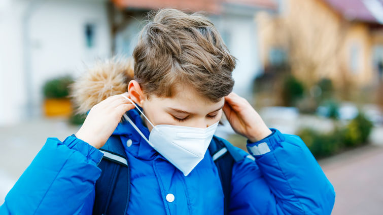 Young boy removing medical face mask