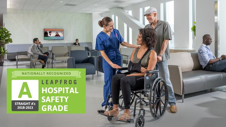  woman in wheelchair, pushed by a man, standing next to female in blue scrubs