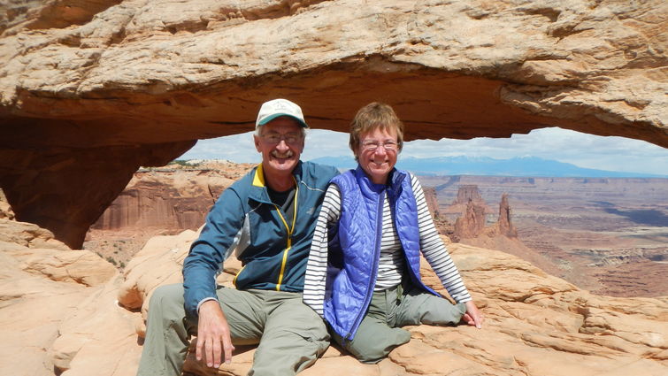 Caucasian couple in their 60s atop a giant rock in the daylight