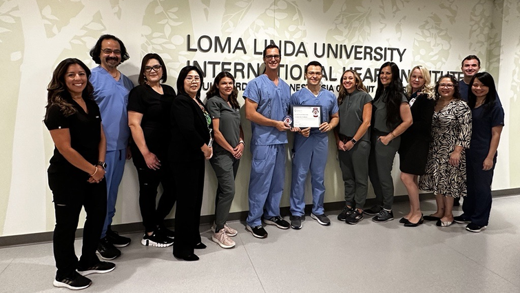 Care team members of the Structural and Valvular Heart Disease program at Loma Linda University Medical Center gather around and pose with their certification from the American College of Cardiology for transcatheter valve care in adult cardiac patients.