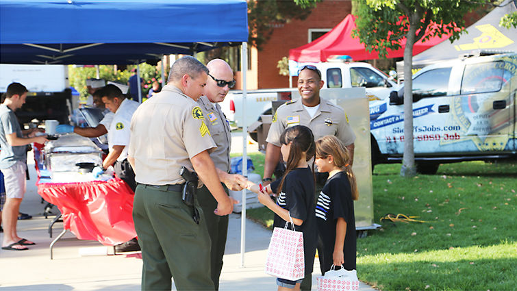 Officers make jokes with two girls who attended National Night Out. Police officers interact with children during National Night Out event