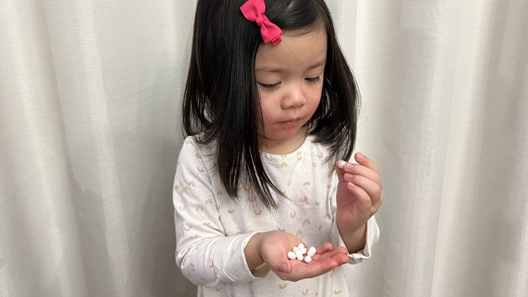 Young girl holding candy that looks like medication in her hands