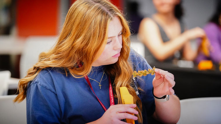 female sitting at a table wearing a navy shirt studying a specimen