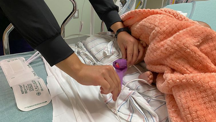 A nurse in the pediatric emergency department at LLU Children’s Hospital checks the blood pressure of a baby with RSV. Baby's foot used to check blood pressure by nurse in hospital