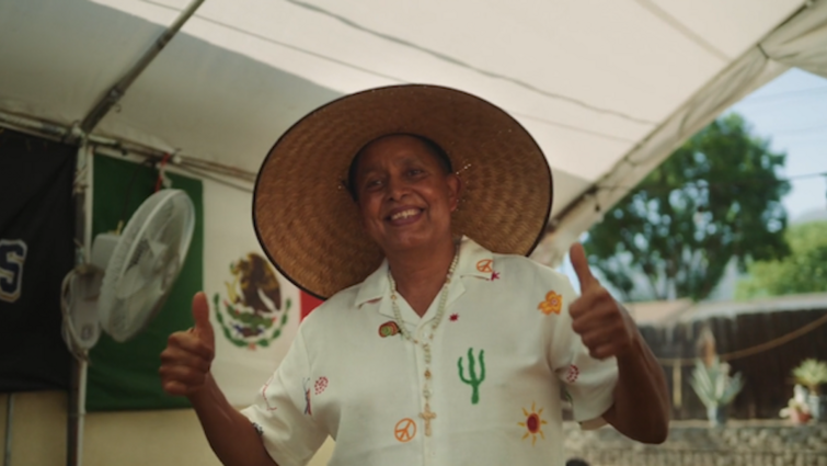 Patient jose Espinoza wearing a hat is facing the camera giving two thumbs up 