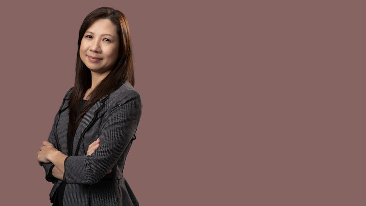 Asian woman in black and white business suit standing with arms crossed