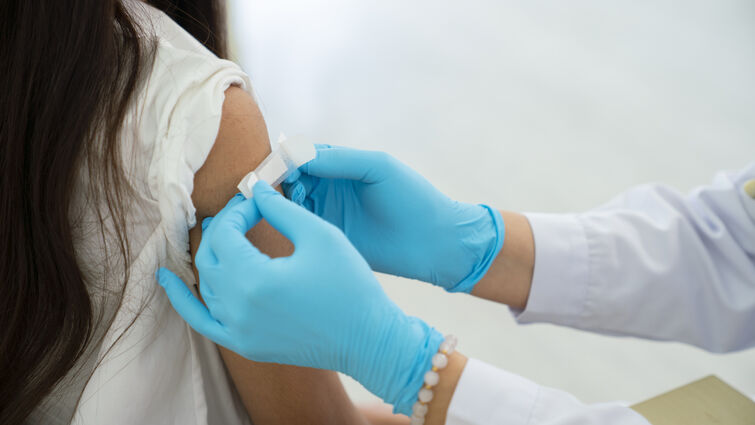 Doctor applies bandage to girl's arm following an immunization
