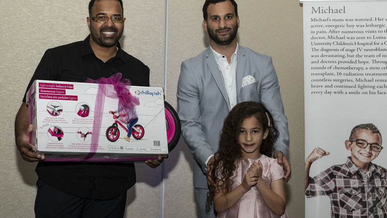 father stands with daughter while she is presented with bike