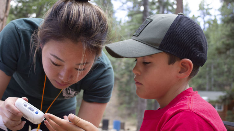 Amy Myung Song, a fourth year student at LLU School of Pharmacy, helps camper Cole Hoelker test his glucose level at Camp Conrad Chinnock on July 24.