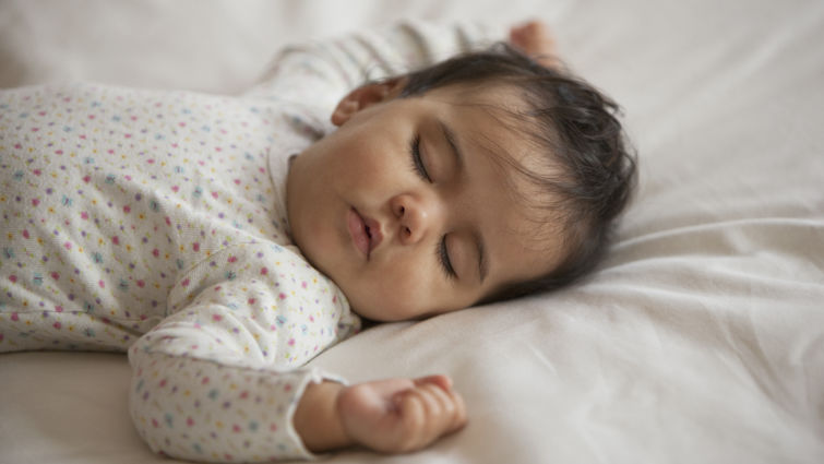 Mixed race baby girl sleeping on bed
