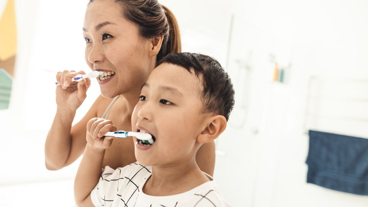 mom with son brushing teeth